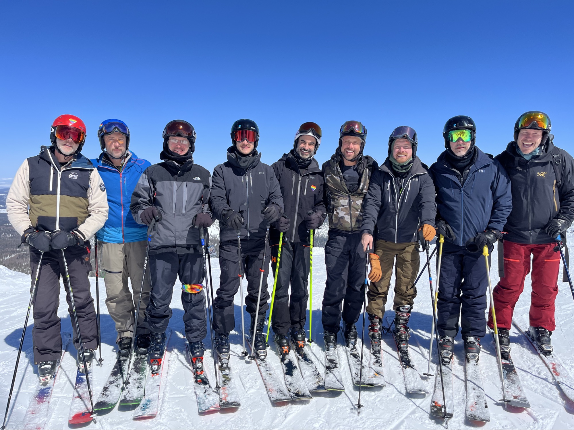 Agroup of men in skiing outfits and skis getting ready to hit the slopes.